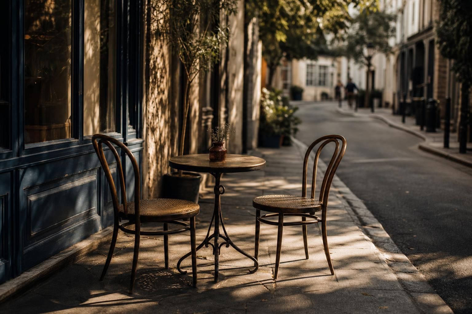 Kleiner Cafetisch mit zwei einander zugewandten Stühlen im Sonnenlicht